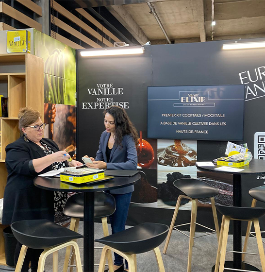 Échange avec une visiteuse sur le stand Eurovanille lors d'un salon professionnel.