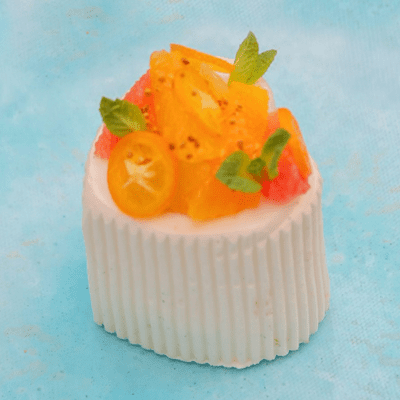 Petit gâteau crémeux au riz et à la vanille surmonté d'agrumes confits et de feuilles de menthe.